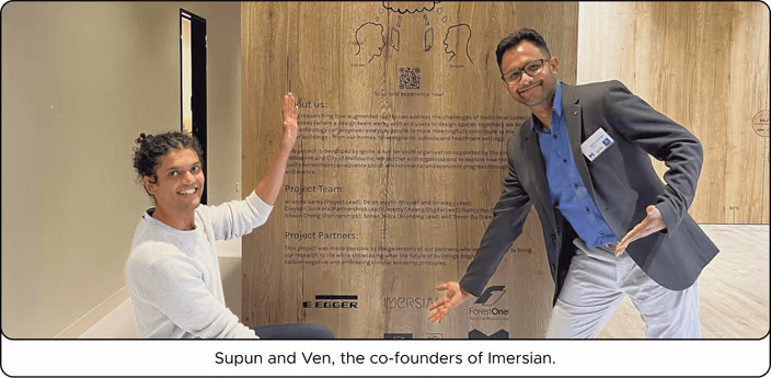 Supun and Ven, the co-founders of Imersian, standing in front of a wooden wall with project partner logos.