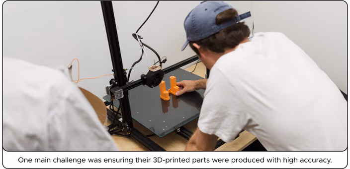 Person testing an orange 3D-printed component on a printer to ensure high accuracy and proper tolerances.
