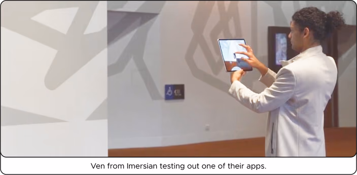 Ven from Imersian testing an augmented reality app on a tablet in a modern indoor space.